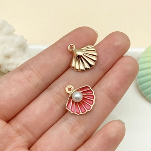 Detailed macro view of pink enamel shell charms with imitation pearls for DIY jewelry