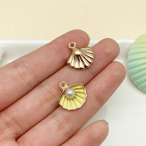 Detail of shell alloy pendants with white pearl and yellow enamel for DIY jewelry