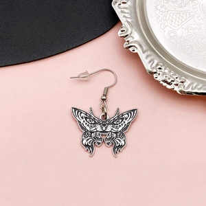 Silver butterfly earrings with black enamel detail and vintage tray background
