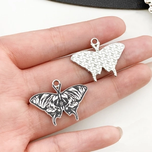 Macro view of butterfly alloy charms with black and white enamel details in hand