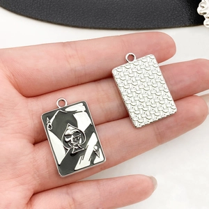 Detail of spade ace charm with skull inlay and hammered silver metal texture