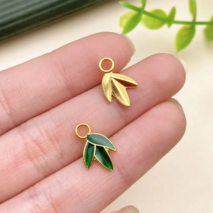 Detail view of bamboo leaf pendant in matte gold finish with green enamel accent