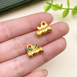 Macro shot of bamboo-shaped gold pendants with vibrant green enamel leaves detail