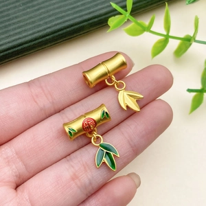 Detailed close-up of matte gold bamboo pendants with enamel leaves and Fu character