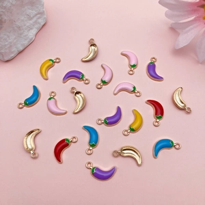 Macro detail of colorful enamel chili pepper charms with golden textured backings