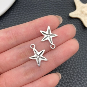 Détail de deux pendentifs étoile de mer argentés avec texture réaliste en main