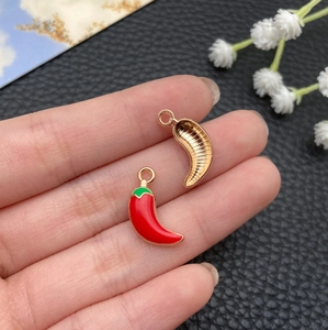 Detail of red chili enamel pendants showing vibrant finish and golden metal backing