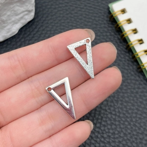 Dettaglio di ciondoli triangolari in argento con texture liscia e opaca per creare gioielli