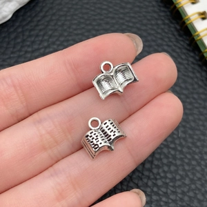 Dettaglio di ciondoli a forma di libro in argento antico con texture per gioielli DIY