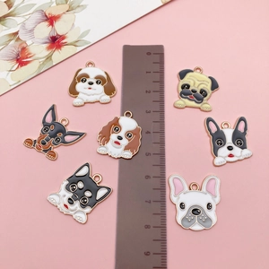 Vue à plat de sept breloques de chiens en émail avec une règle pour la mesure