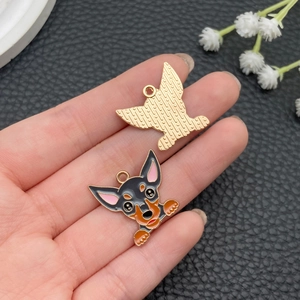 Détail d'un pendentif chien en émail avec dos doré texturé et anneau de suspension