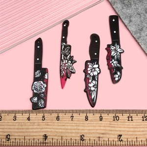 Detailed macro of acrylic knife charms with black floral patterns and red blood splatters
