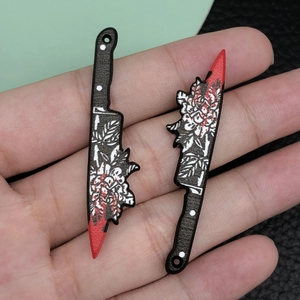 Macro detail of acrylic knife charms with white flower patterns and red blood splatter