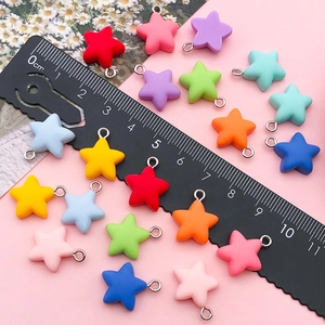 Colorful resin star charms with metal rings for DIY jewelry making on a pink background