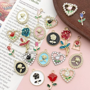 Detailed close-up of multi-colored enamel rose charms with pearls on a wooden tray