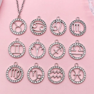 Collezione di ciondoli zodiacali in argento lucido con cristalli su sfondo rosa