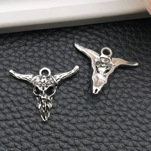 Detailed macro view of vintage silver bull skull pendants showing front and back textures