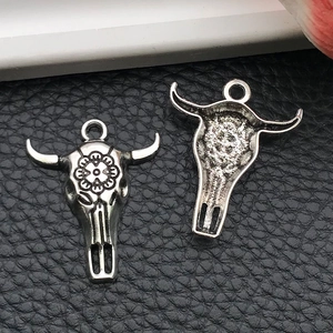 Detail view of antique silver bull skull charms showing floral engraving and hollow back