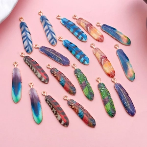 Détail macro de pendentifs plumes émaillés multicolores pour sets bijoux DIY
