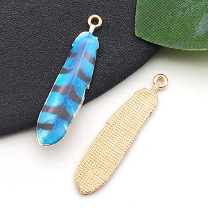 Vue macro détaillée du pendentif plume avec recto bleu rayé et verso doré avec texture maille