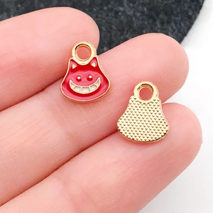Detalle de colgantes gato de esmalte rojo con reverso dorado y comparación de tamaño