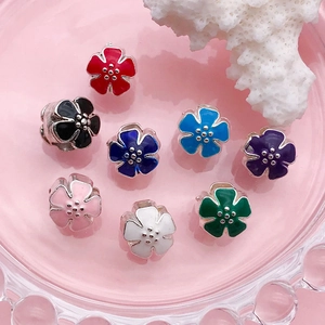 Detalle macro de ocho dijes de flores en esmalte colorido para pulseras de DIY