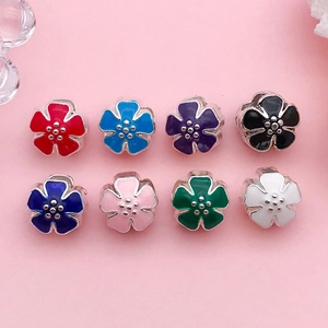Detalle macro de ocho cuentas de flores coloridas en aleación con esmalte para joyería DIY