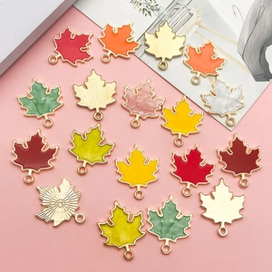 Flat lay of seventeen colorful maple leaf enamel pendants for DIY jewelry crafting