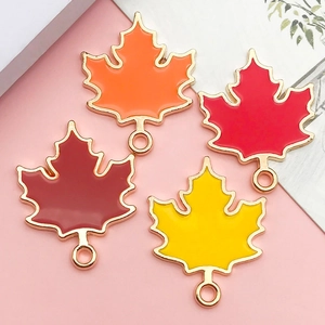 Detail of four colorful maple leaf enamel charms in red, orange, and yellow for DIY jewelry