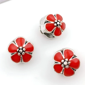 Detalle de tres cuentas de flores en esmalte rojo con agujero grande para pulseras DIY