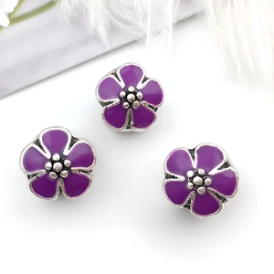 Detalle de tres abalorios de flores de esmalte morado para joyas DIY y pulseras