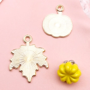 Detailansicht der goldenen Ahornblatt-Anhänger und Kürbis-Charm für DIY-Schmuckherstellung