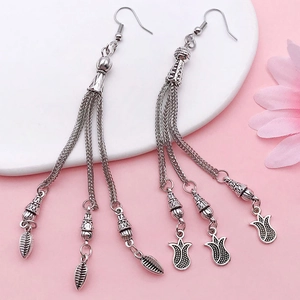 Detail of vintage silver moon and flower tassel charms with dangling metal leaves