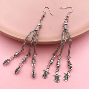 Detail view of ethnic style long fringe earrings with antique silver floral pendants