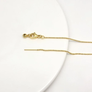 Dettaglio catena a sfere in oro 14k con chiusura a moschettone e ago regolabile sottile