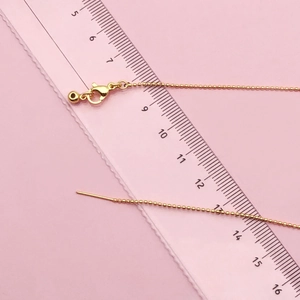 Catena a sfere placcata oro 14k con chiusura a moschettone e ago su un righello