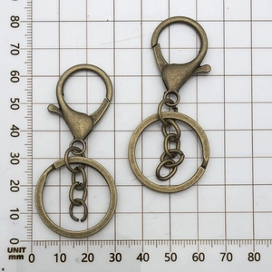 Detail showing vintage bronze lobster clasp with key ring and chain on a grid background
