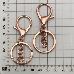Detail view of rose gold plated keychain ring and lobster clasp over measurement scale