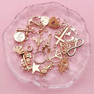 Assorted gold alloy DIY charms including anchor, heart and star on a frosted plate