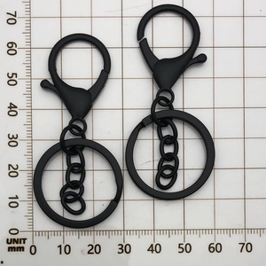 Detailed view of matte black lobster claw keychain with 4-link chain on scale ruler