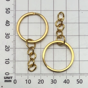 Close-up of golden electroplated DIY keychain rings with 4-link chains on a measuring grid