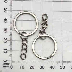 Close-up of metal key rings with short link chains on a metric measurement grid