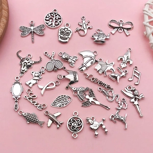 Détail de divers pendentifs DIY en alliage d'argent antique sur fond rose poudré