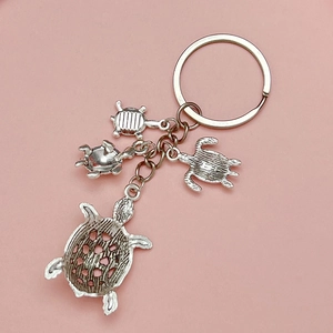 Porte-clés tortue marine avec quatre pendentifs en alliage argenté sur fond rose