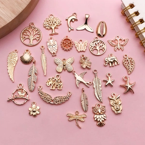 Flat lay of rose gold alloy charms with tree, owl, and butterfly for DIY jewelry making