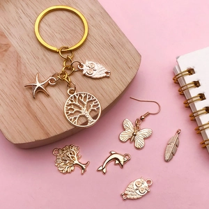 KC gold alloy charm collection with starfish, owl, and tree pendants on pink background