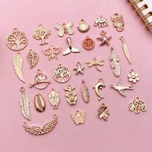 Flat lay of mixed rose gold alloy pendants for DIY jewelry making on pink background