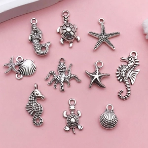Close-up of vintage silver marine animal charms for DIY jewelry on pink background