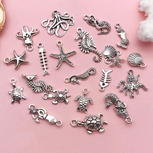 Flat lay of vintage silver ocean-themed charms including seahorse and starfish for DIY jewelry