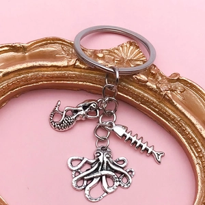 Detailed close-up of silver ocean charms featuring a mermaid, fishbone, and octopus on a keyring